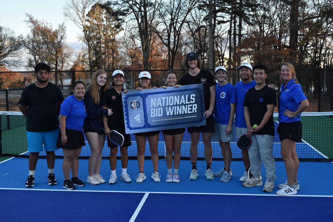 A collegiate pickleball club poses on court with their Nationals bid banner