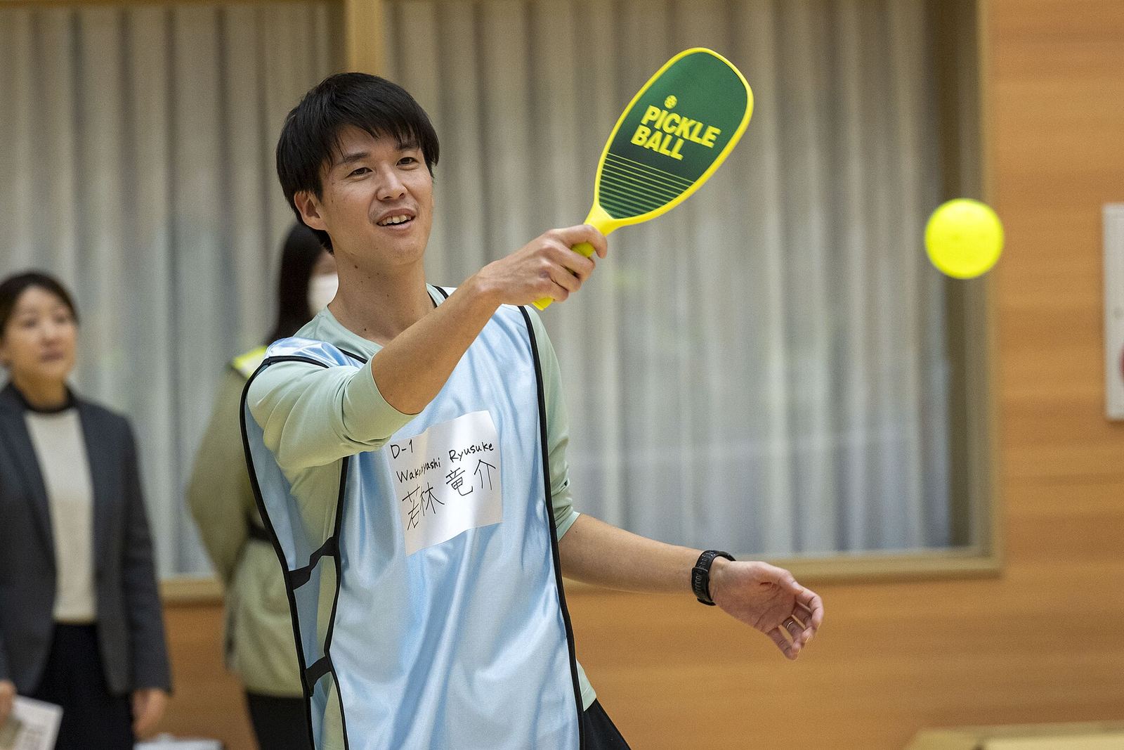 A smiling player watches the ball after a paddle hit